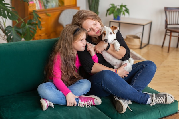 Ritratto di una mamma adorabile e della sua piccola figlia e abbracci di cane che trascorrono il tempo libero insieme seduti