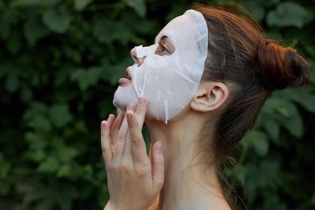 Ritratto di una maschera bianca della ragazza all'aperto vista laterale spalla nuda spalle nude