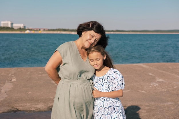 Ritratto di una nonna con la nipote che trascorre il fine settimana e cammina sulla costa in estate soleggiata