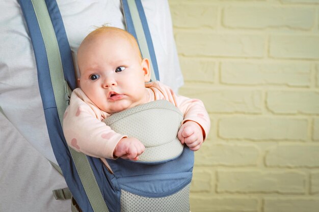 Ritratto di una piccola bambina carina in una fionda che guarda la telecamera