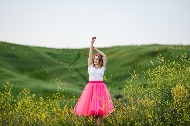 Ritratto di una principessa ragazza seria in un paese La ragazza in un abito rosa cammina a piedi nudi sull'erba verde nel campo