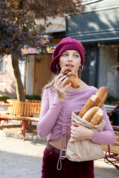 Ritratto di una ragazza adolescente che mangia un croissant fresco lasciando una panetteria