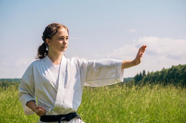 Ritratto di una ragazza adolescente che pratica il karate kata all'aperto
