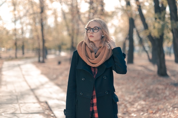 Ritratto di una ragazza adolescente in grandi occhiali neri in un parco in autunno