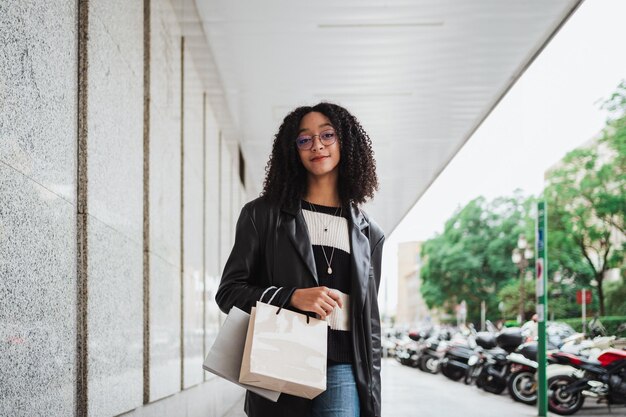 Ritratto di una ragazza afro con gli occhiali che sta andando a fare shopping Sta guardando la macchina fotografica