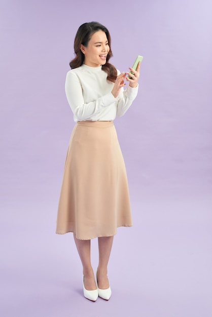 Ritratto di una ragazza allegra che guarda il telefono cellulare isolato su sfondo viola