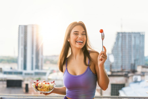 Ritratto di una ragazza allegra felice che mangia insalata fresca dalla sua ciotola