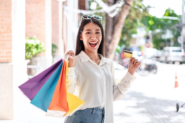ritratto di una ragazza asiatica che sorride con in mano le borse della spesa che si divertono nello shopping espressione rilassata