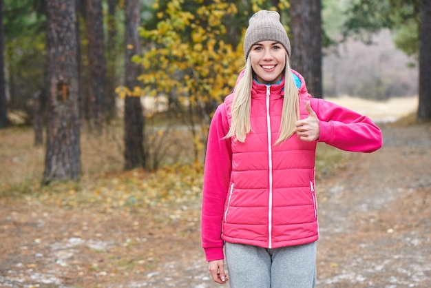 Ritratto di una ragazza atleti in giacca e berretto nel bosco. Uno stile di vita sano