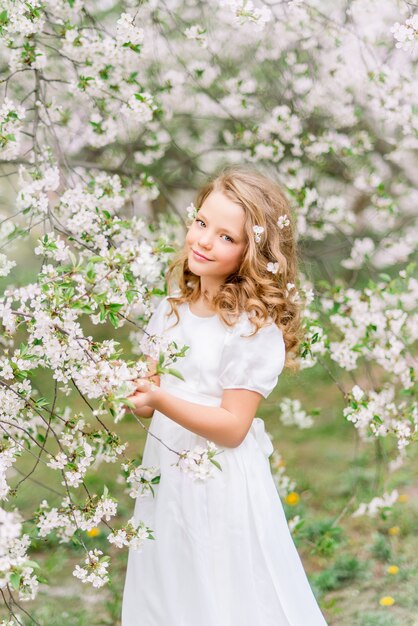 Ritratto di una ragazza bellissima modella in un giardino fiorito. Fiori bianchi tra i capelli