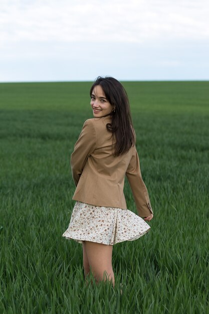 Ritratto di una ragazza bruna allegra positiva in un parco di primavera verde.