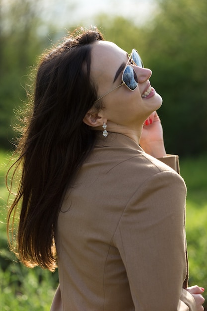 Ritratto di una ragazza bruna allegra positiva in un parco di primavera verde.