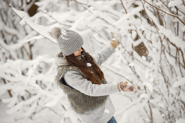 Ritratto di una ragazza bruna con cappello lavorato a maglia e giacca grigia in inverno