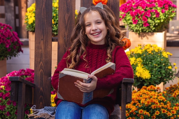 ritratto di una ragazza carina con un libro in autunno su una panchina