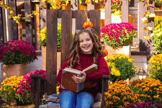 ritratto di una ragazza carina con un libro in autunno su una panchina