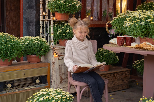 ritratto di una ragazza carina in autunno in giardino con un libro e fiori