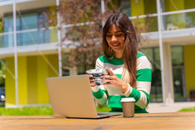 Ritratto di una ragazza caucasica che lavora con un computer in natura e rivede le foto