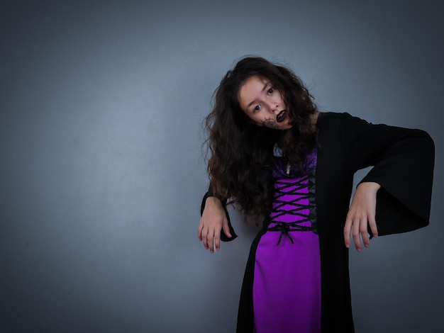 Ritratto di una ragazza caucasica in abito da strega su grigio scuro