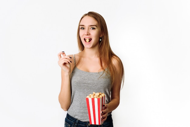 Ritratto di una ragazza che ride in abiti casual tenendo la scatola di popcorn e guardando la fotocamera