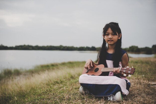 Ritratto di una ragazza che suona l'ukulele sul campo