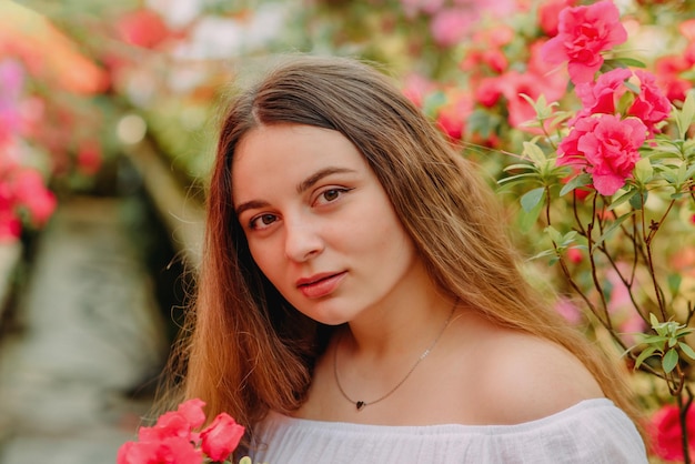 Ritratto di una ragazza con fiori in una serra con azalee