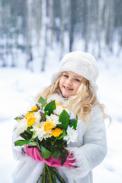 Ritratto di una ragazza con un mazzo di fiori nella foresta in inverno