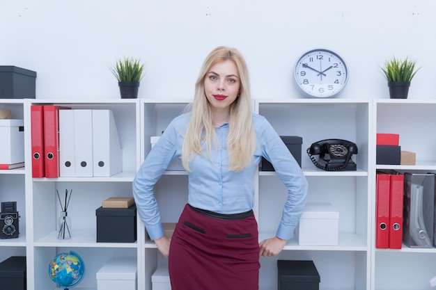 Ritratto di una ragazza con una camicia blu e una gonna rossa in ufficio