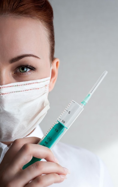 Ritratto di una ragazza con una maschera medica Tenendo una siringa in mano Close upxA