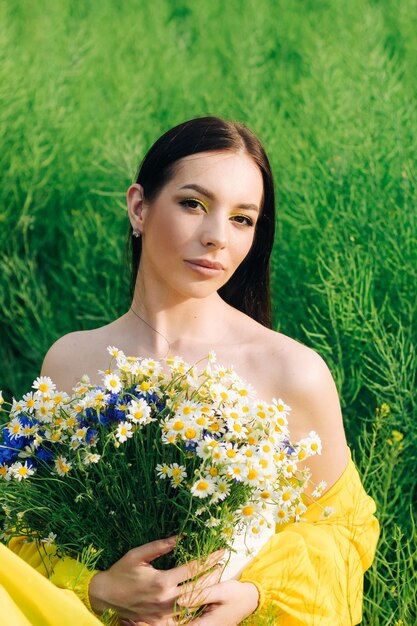 Ritratto di una ragazza dai capelli scuri con un mazzo di fiori selvatici