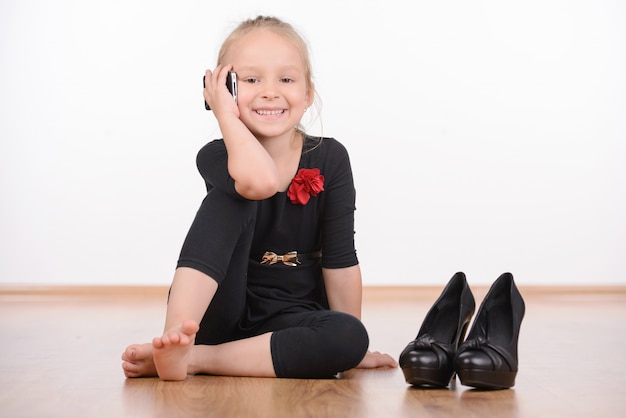 Ritratto di una ragazza di moda in un abito nero e grandi scarpe.