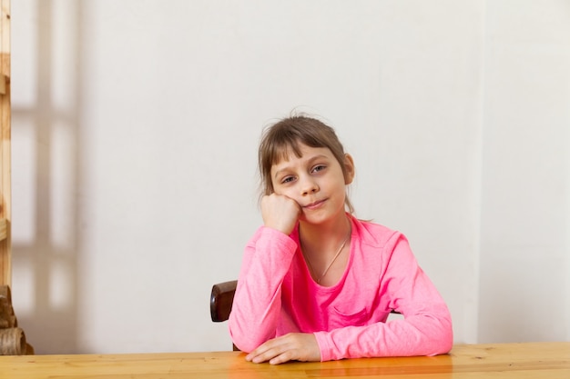 Ritratto di una ragazza di otto anni su una sedia, pensando