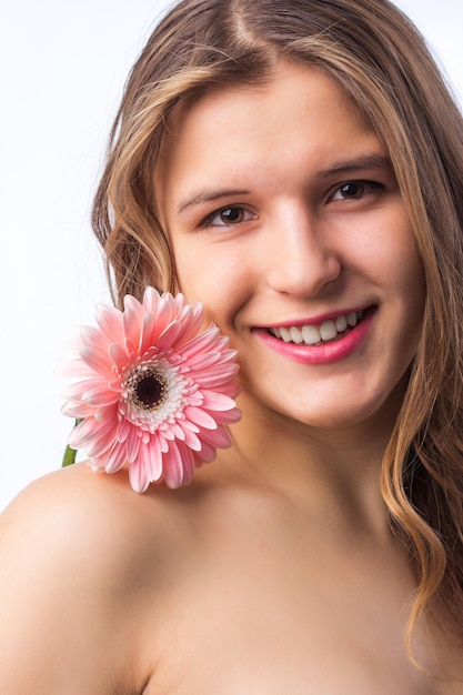 Ritratto di una ragazza felice con la pelle fresca che tiene un fiore su un occhio su sfondo bianco Close up ritratto di bella donna riccia rossa pnik fiore che indossa una maglietta bianca Bellezza e primavera