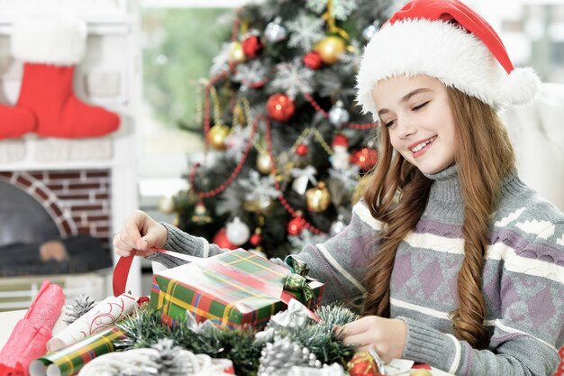 Ritratto di una ragazza felice con un cappello da Babbo Natale seduto con un regalo di Natale