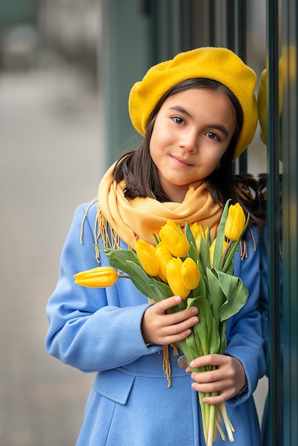 Ritratto di una ragazza felice con un mazzo di tulipani gialli in una passeggiata in primavera fiori per l'internazionale