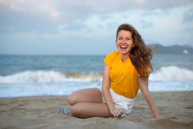 Ritratto di una ragazza felice, una giovane donna spensierata che si gode le vacanze estive in mare, che cammina sulla sabbia della spiaggia.