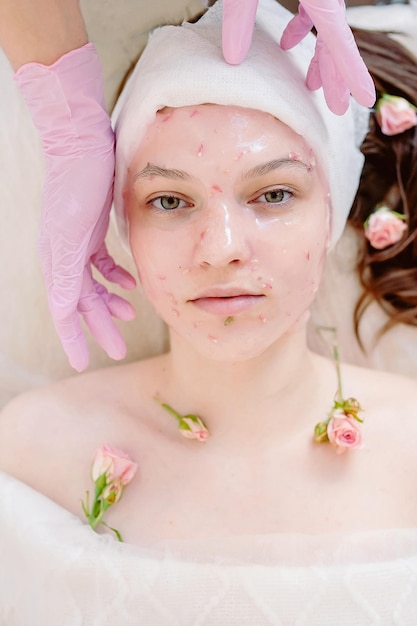 Ritratto di una ragazza foto dall'alto con una maschera di alginato applicata le mani dell'estetista le toccano il viso