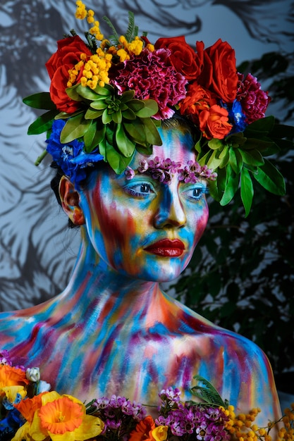 Ritratto di una ragazza il cui viso è dipinto con vernici colorate in una corona di fiori. Sulle orme di Frida Kahlo