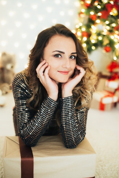 Ritratto di una ragazza in abito da sera sullo sfondo delle decorazioni natalizie