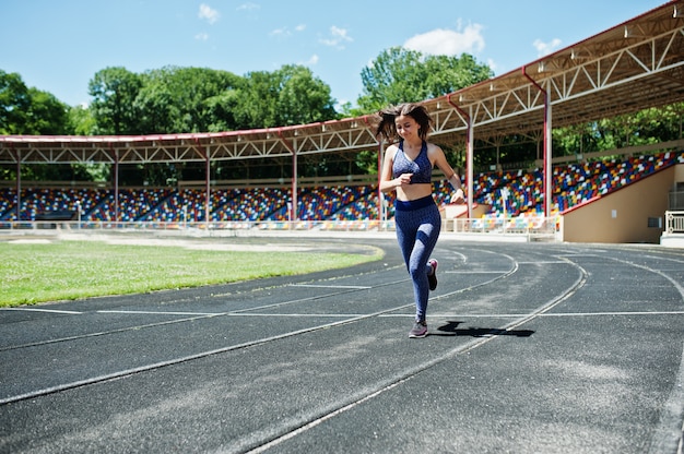 Ritratto di una ragazza in forma forte in abiti sportivi in esecuzione nello stadio.