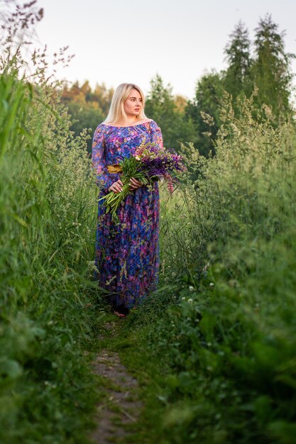 Ritratto di una ragazza in un campo fiorito al sole al tramonto