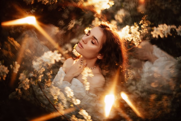 Ritratto di una ragazza romantica, come una ninfa della foresta, in un giardino fiorito con elementi di fantasmagoria. Il concetto di fantasia, fiabe.