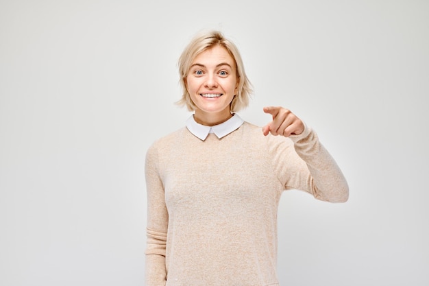 Ritratto di una ragazza sicura sceglie di puntare il dito verso la fotocamera isolata su sfondo bianco studio Il gesto di benvenuto si unisce al nostro concetto di squadra