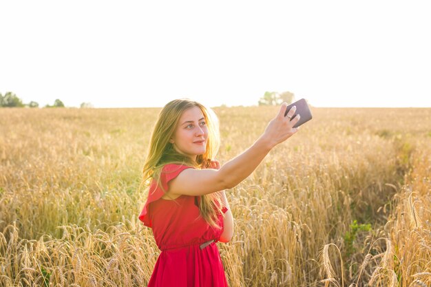 Ritratto di una ragazza sorridente che fa la foto del selfie nel campo