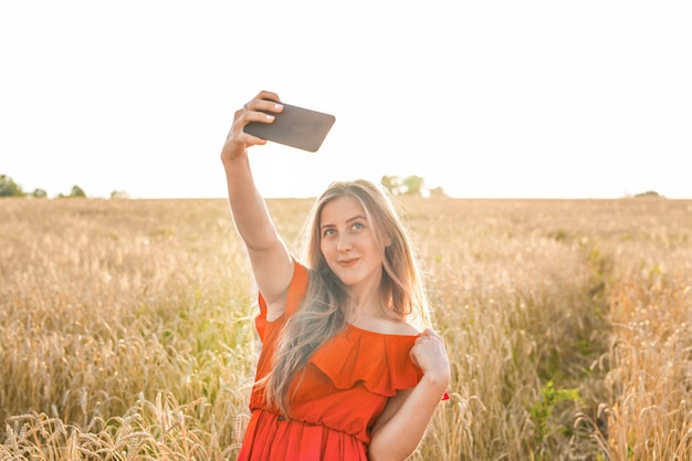 Ritratto di una ragazza sorridente che fa la foto del selfie nel campo