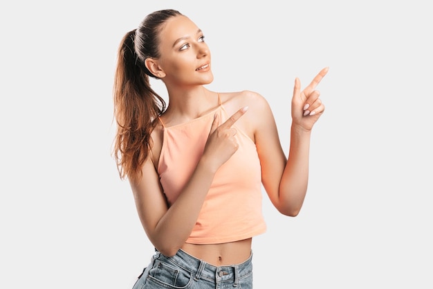 Ritratto di una ragazza sorridente che punta il dito di lato su uno sfondo bianco isolato Donna positiva indica un'idea un luogo per la pubblicità