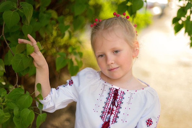 Ritratto di una ragazza sorridente con un fiore in una camicia ricamata ucraina Viburnum nei capelli