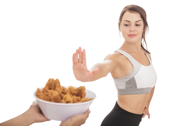 Ritratto di una ragazza sportiva sana sul processo di dieta che rifiuta una ciotola di pollo fritto