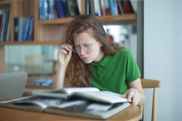 Ritratto di una ragazza stanca e sovraccarica di lavoro, una giovane donna esausta con gli occhiali, una studentessa universitaria o universitaria.
