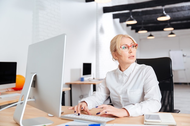 Ritratto di una seria imprenditrice matura, lavorando in ufficio con il computer