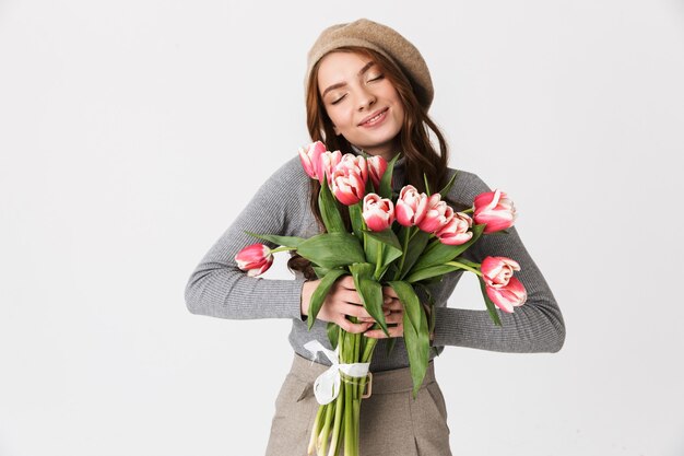 Ritratto di una splendida donna anni '30 che indossa un cappello con in mano un mazzo di bellissimi fiori isolati su bianco